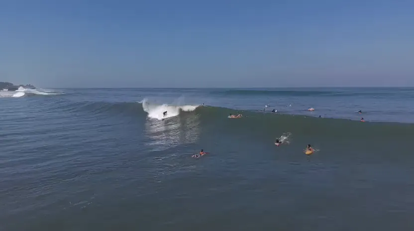 Surfers waiting in the lineup as a wave breaks in Santa Teresa