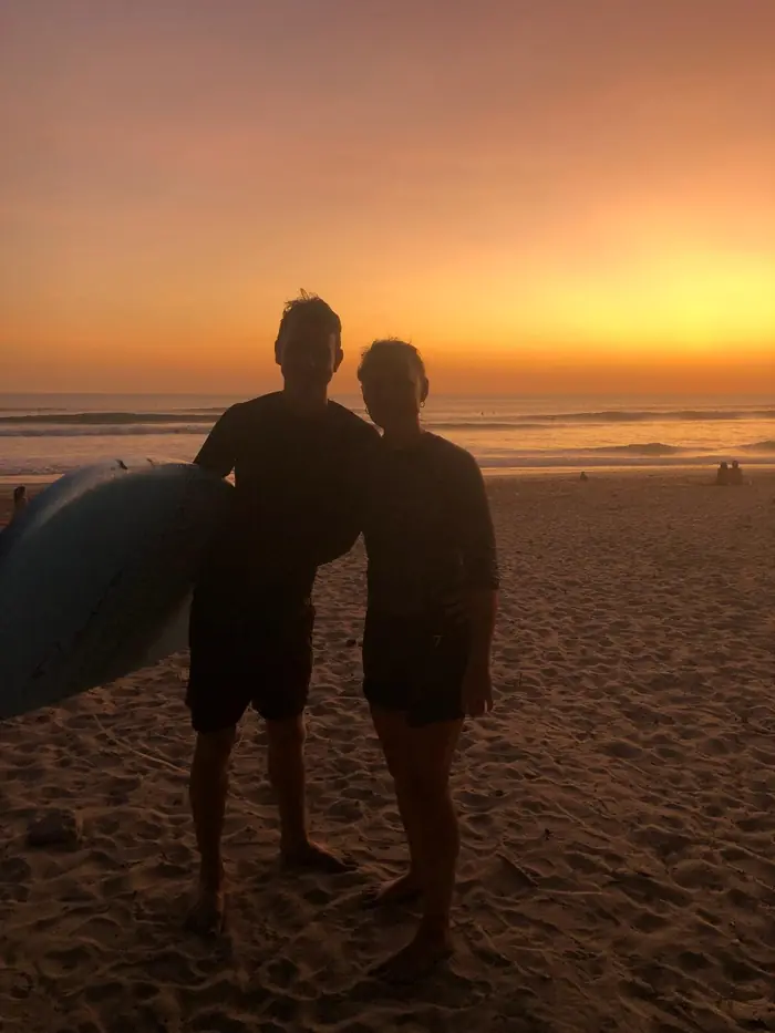 Two surfers on the beach at sunset