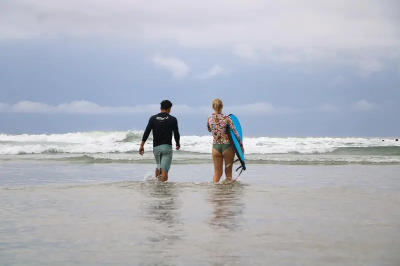 Weyser and a student walking into the ocean together with their boards