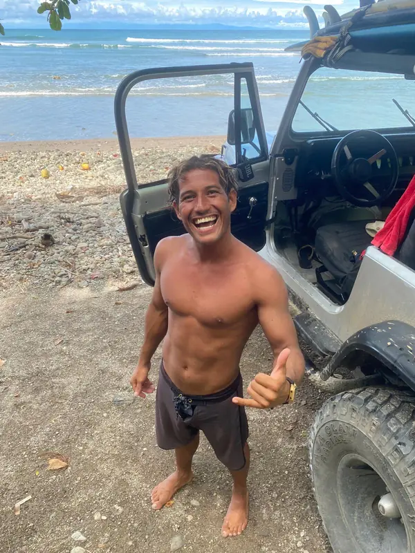 Weyser laughing and throwing a shaka next to his jeep on the beach